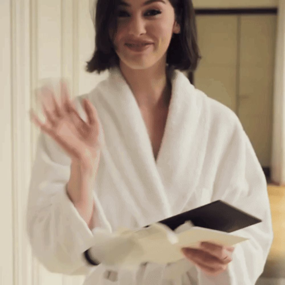 a woman in a white robe is holding a book and a card