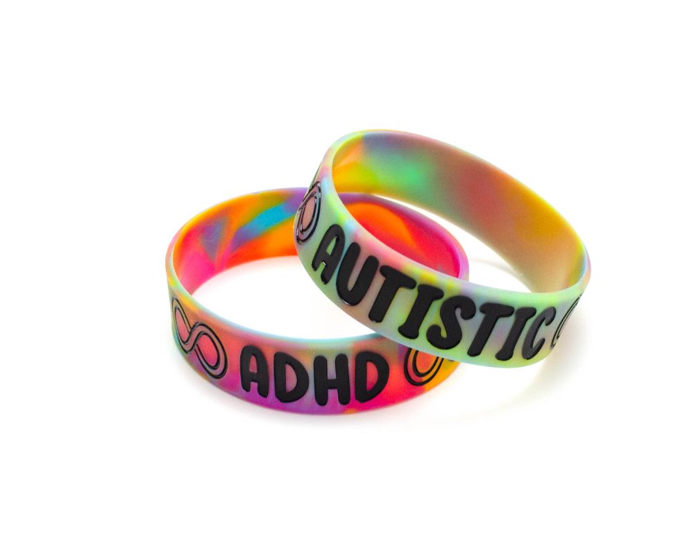 multicoloured silicone wristbands with black text. one says ADHD and one says AUTISTIC