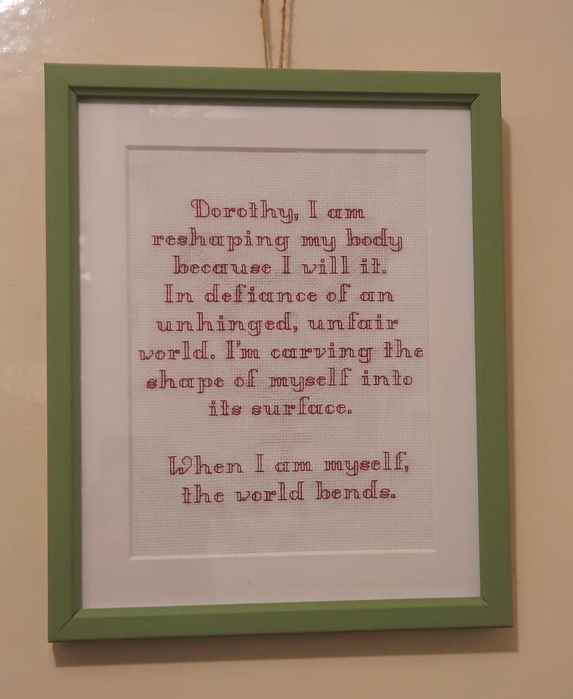 maroon embroidery in a green frame which reads 