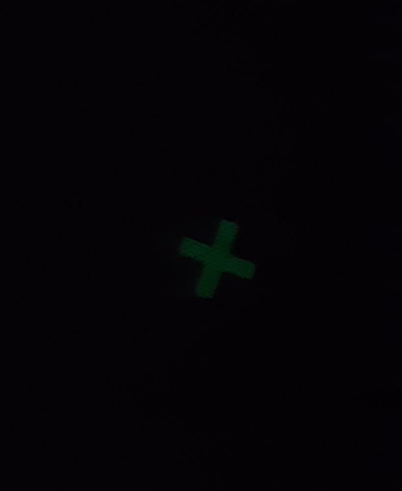 A completely black photo with a green glowing X in the middle
