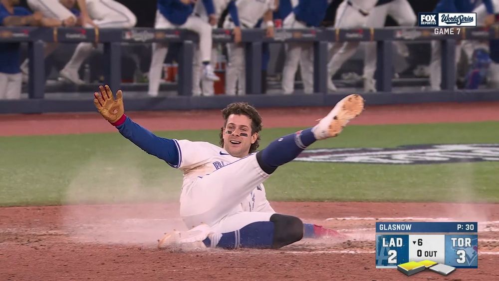 Ernie Clement giddily sliding into home with his right arm extended and left leg kicking up and out like he's dancing