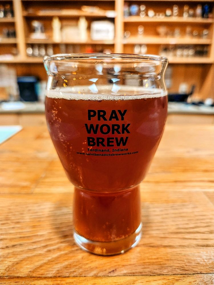 Glass of beer the at reads Pray Work Brew