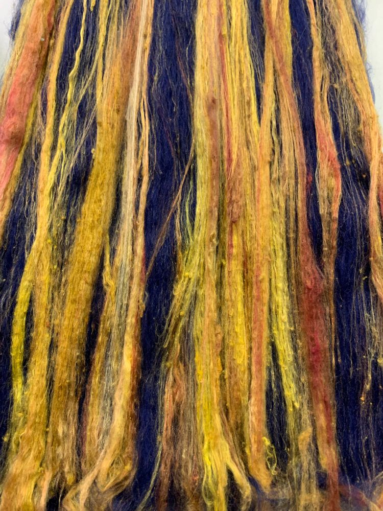 A carded blue merino wool batt with bright stripes of yellow and orange silk. 