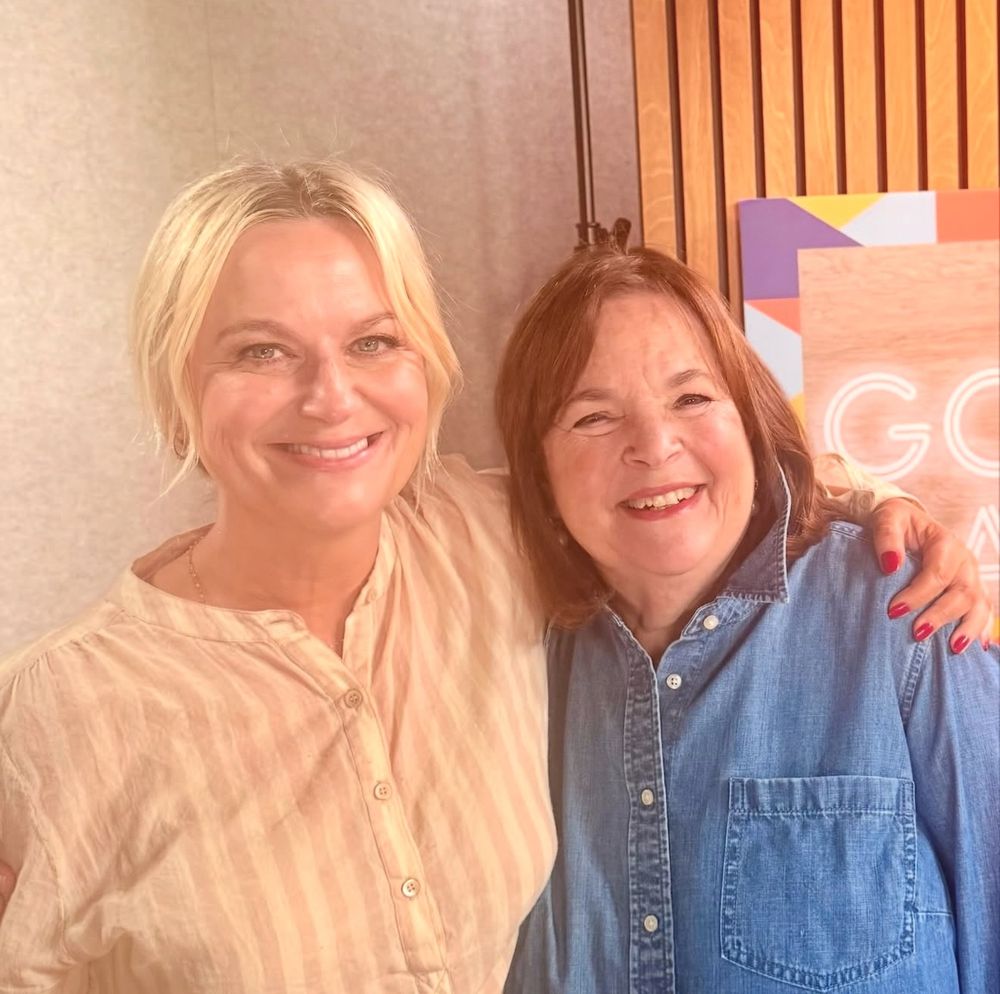 Amy Poehler and Ina Garten pose for a photo together. Amy’s hand is over Ina’s shoulder.