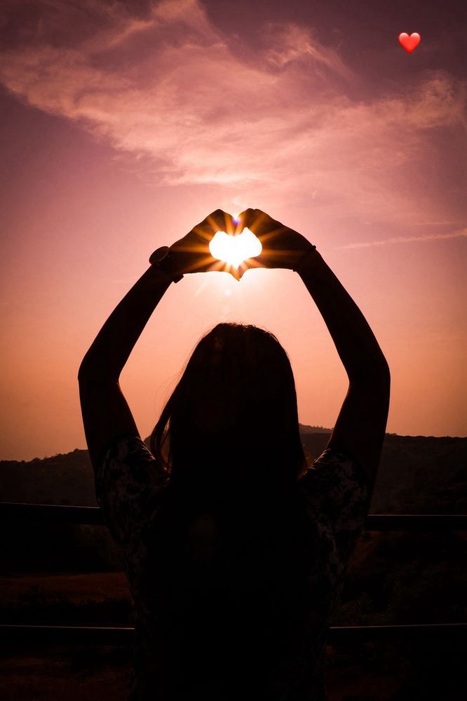 Das Bild zeigt eine Frau von hinten die ihre Arme hoch in den apricot-lachsfarbenen Sonnenuntergang streckt und ein Herz mit ihren Händen formt . Durch das Herz leuchtet die Sonne. Es sind nur die Arme und der Kopf zu sehen, da die unter Hälfte 
des Bildes schwarz ist.
Es macht einen romantischen Eindruck.