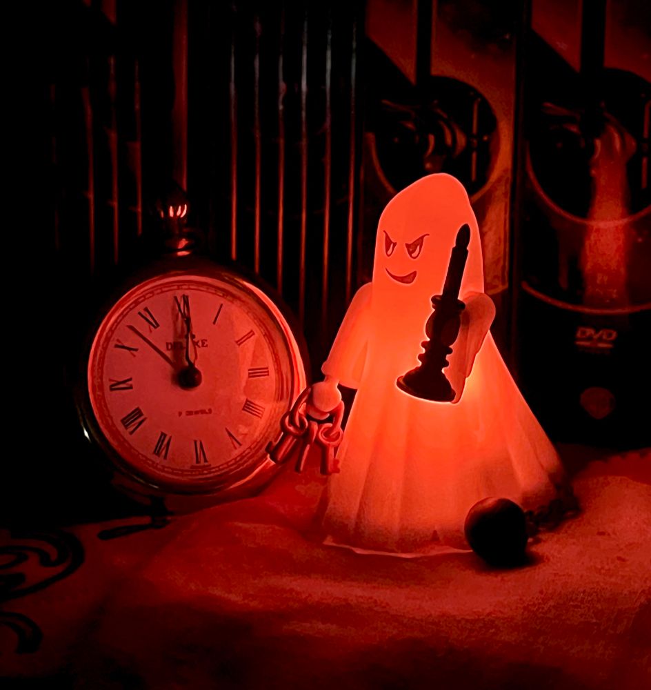 Im Dunkeln steht ein rot glühender Playmobil-Geist neben einer alten Uhr, die natürlich auf 0:00 Uhr steht und vom Geist rot angeleuchtet wird