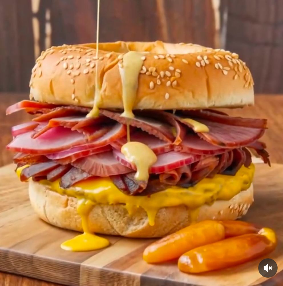 an AI image of a pastrami sandwich. not to overuse the word non-euclidean but what else can I say to describe these layers of meat? this one also has some kind of yellow sauce leaking out of the bottom, and another yellow sauce being sensuously drizzled on top. in the lower right corner are baffling tubes that sort of look like if roasted carrots fucked a soft pretzel. 