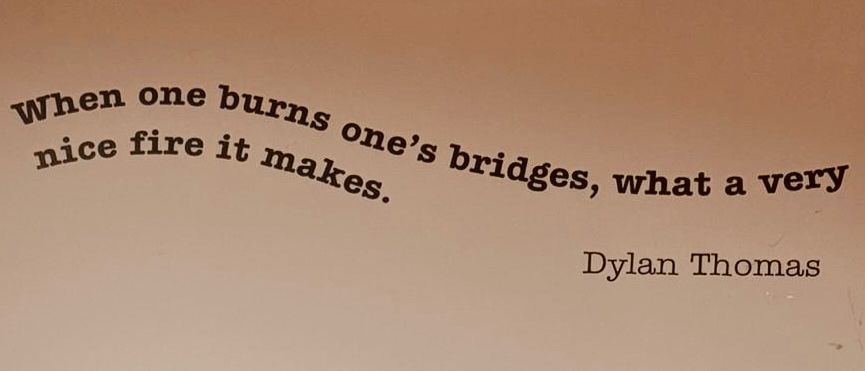 Quote by Dylan Thomas stencilled on a wall that says, “When one burns one's bridges, what a very nice fire it makes.”
