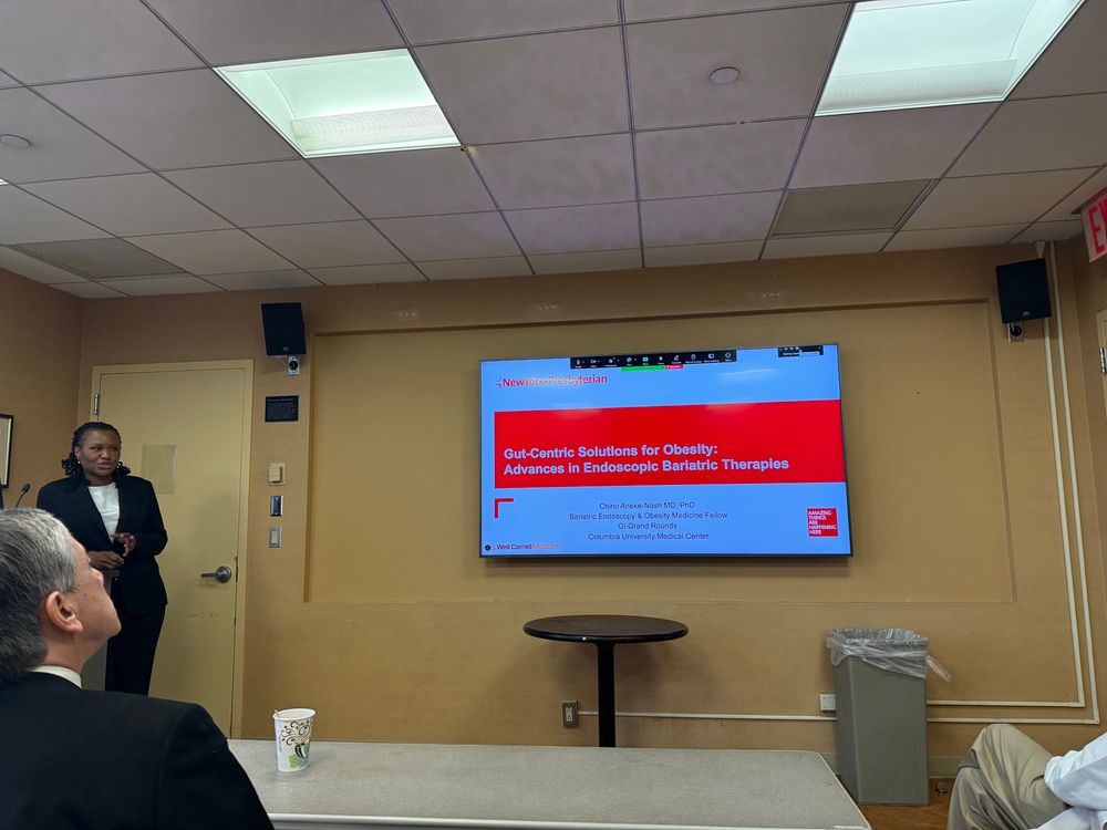Dr Aneke-Nash standing next to a screen with her title slide on endobariatrics
