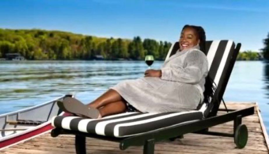 Cirie smiling and lying down, holding a glass of wine on a sun bed 
