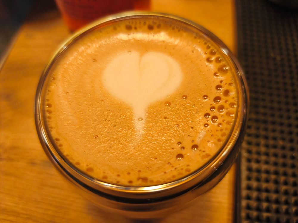Eine Tasse Kaffee mit Milchschaum von oben gesehen. Im Milchschaum ein Herz. Latte Art. 