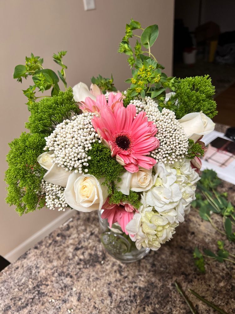 A bouquet of white and pink flowers sits on a countertop.