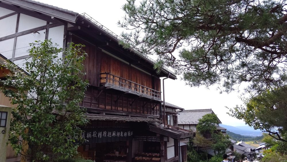 写真　旧中山道の宿場町、馬籠宿の旅籠(はたご)の建物。坂の上から下りを見ている。