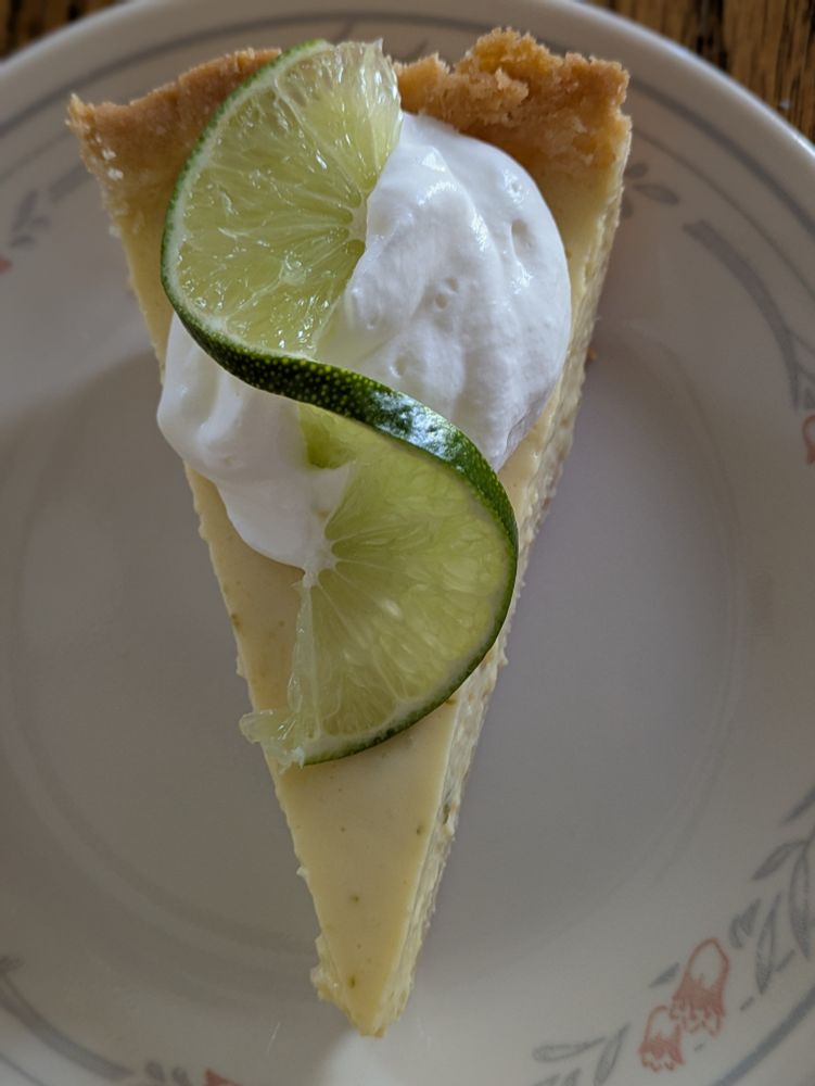 Key lime pie with dollop of whipped cream and twist of lime