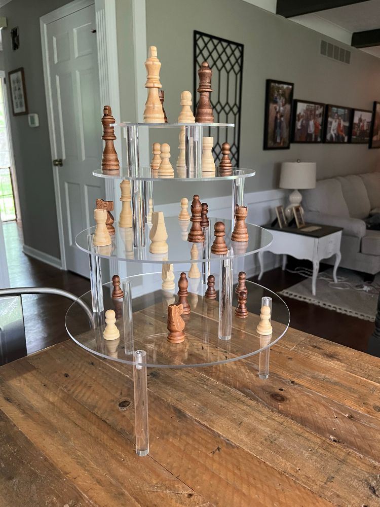 Multiple levels of a plexiglass cake stand with chess pieces on them mimicking the three dimensional chess set from Star Trek