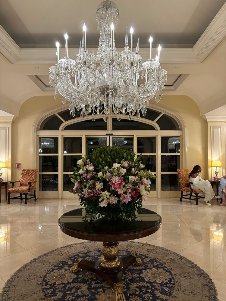 A giant crystal chandelier hangs over a large floral display in the Langham Pasadena hotel lobby