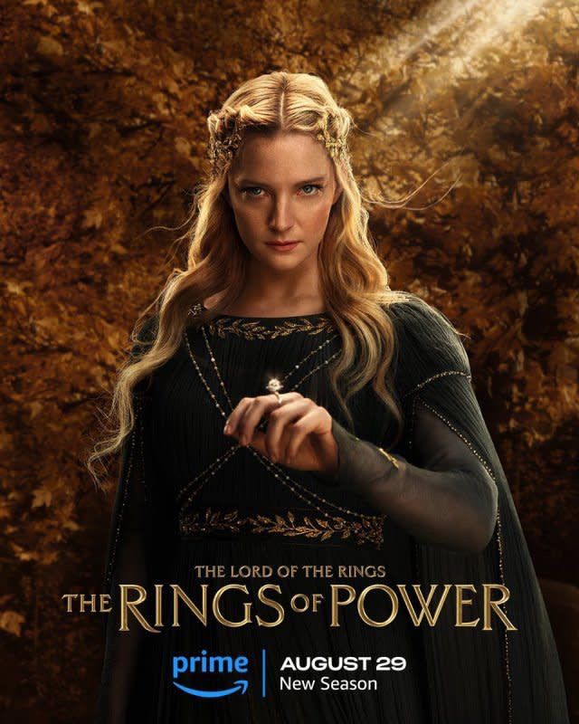 Rings of Power season 2 poster featuring Galadriel in a dark green chiffon dress with golden leaf trim and draped sparkly chains.
