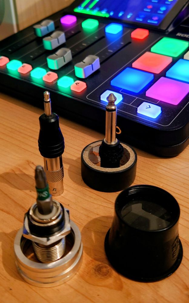 Viele kleine technische Gegenstände sind symmetrisch angeordnet. Dahinter ein Mischpult.