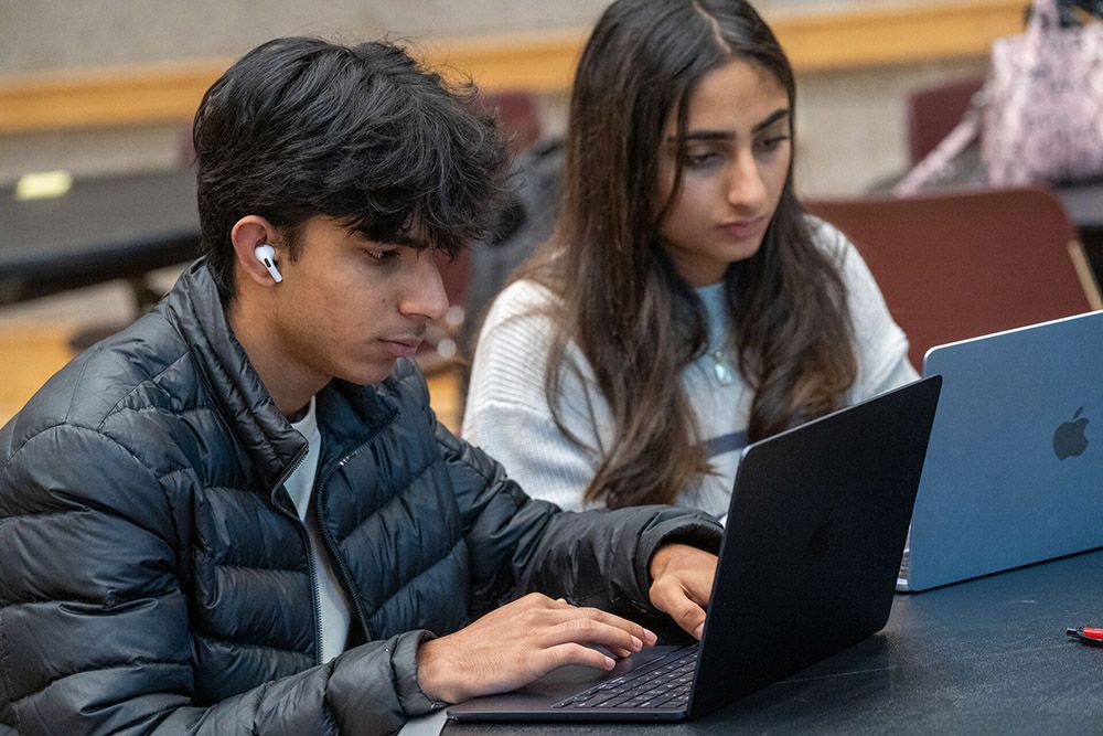 Two students are focused on their laptops at INNOVATE: Honors Edition.