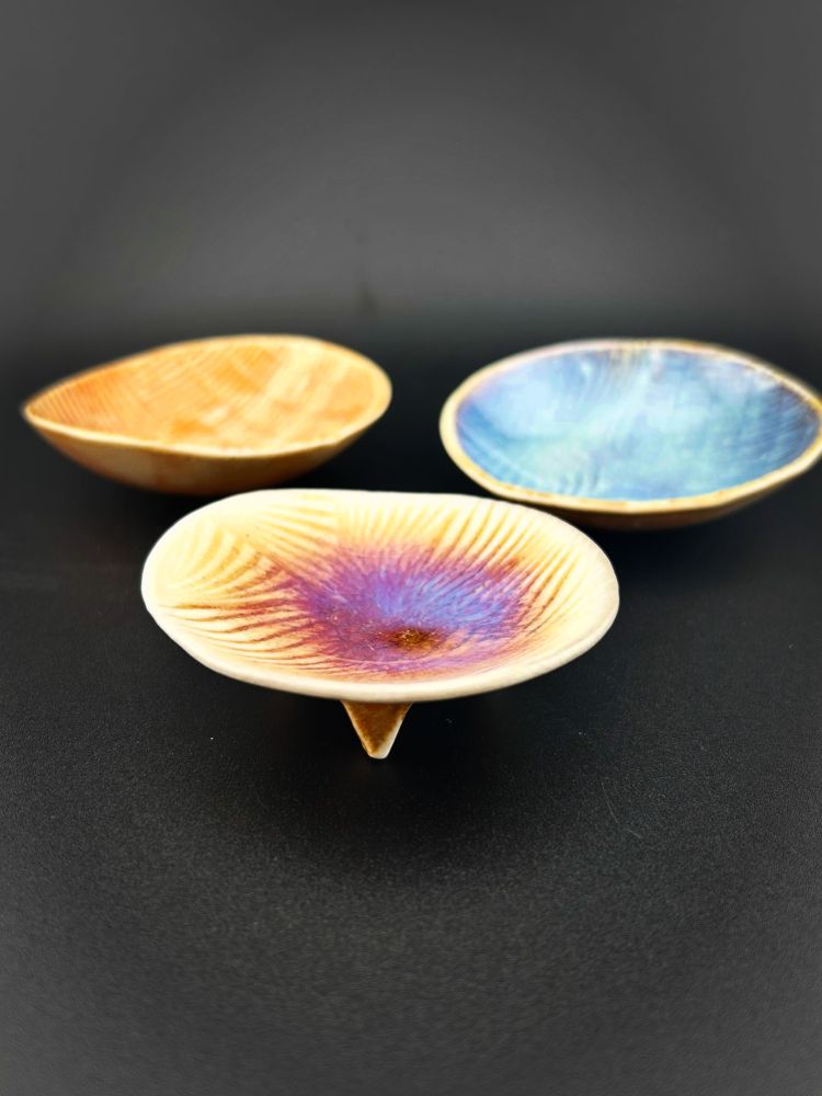 Three small ceramic bowls with color gradation caused by soda ash added to the kiln during firing.