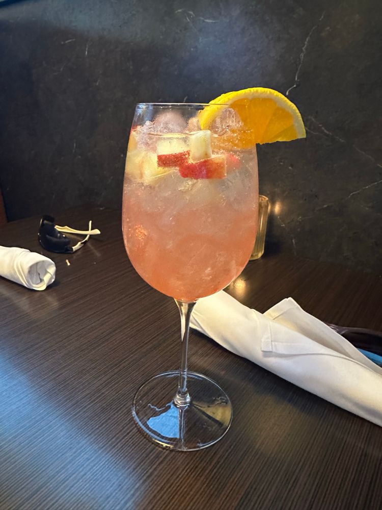 A wine glass with prosecco, peach nectar, and lemon slices.
