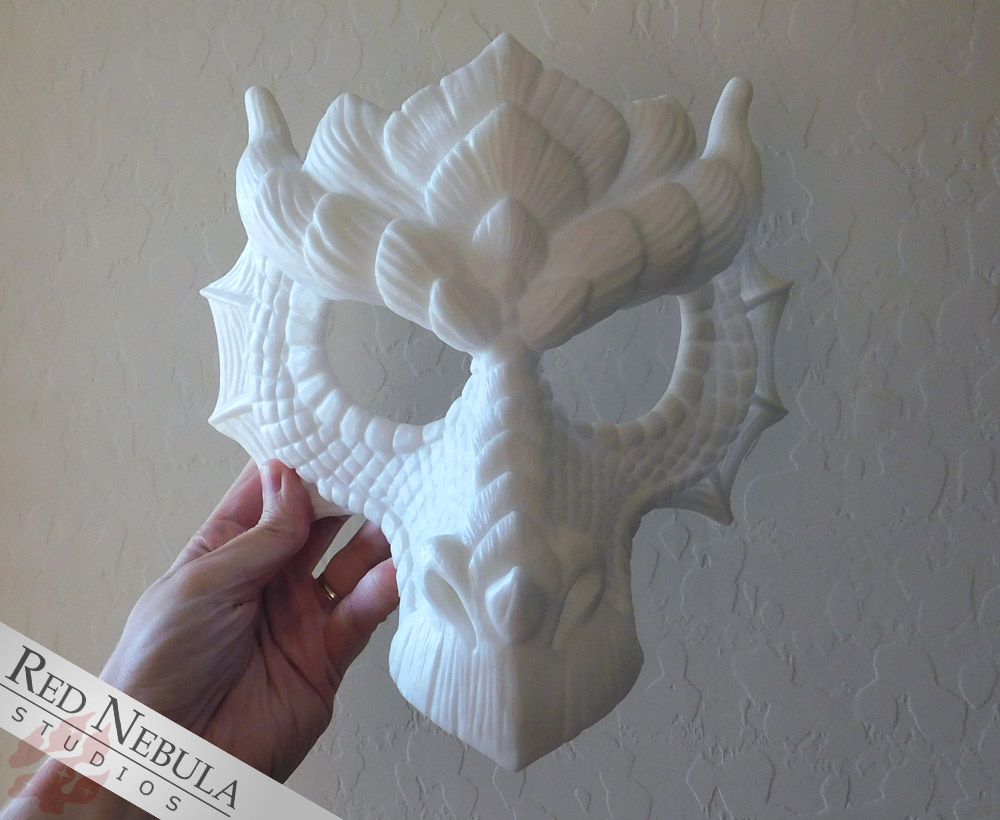 A white, resin-cast dragon mask with detailed scales, held up by a hand.