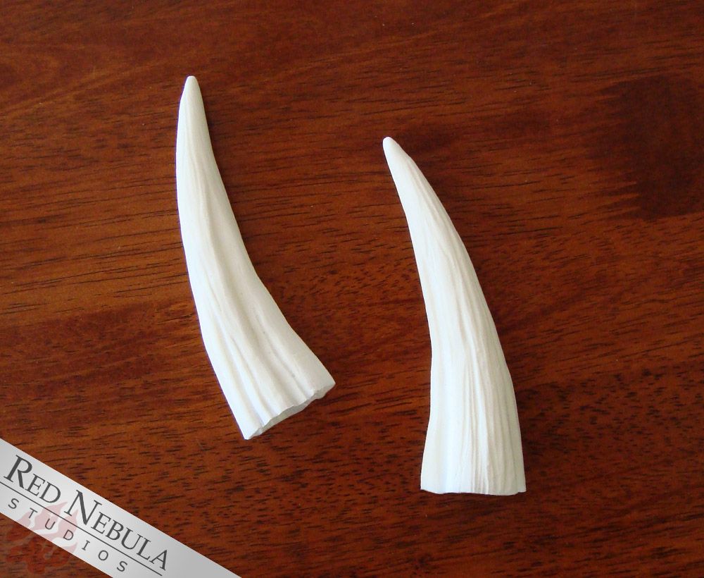 A photo of a pair of long, thin white resin horns.