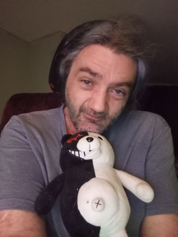 Sylvester, wearing a headset and cuddled up to Monokuma