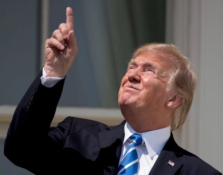 Donald Trump points to eclipse while conspicuously not wearing protective eyewear.