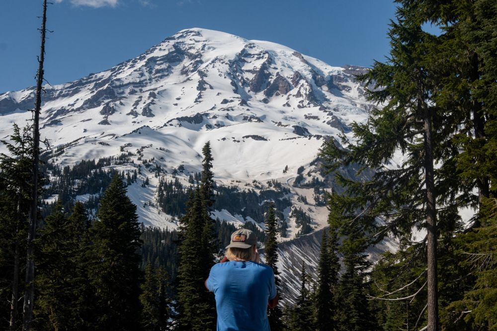 Me standing in front of Mount Rainier shooting a photo of the snowy peak.