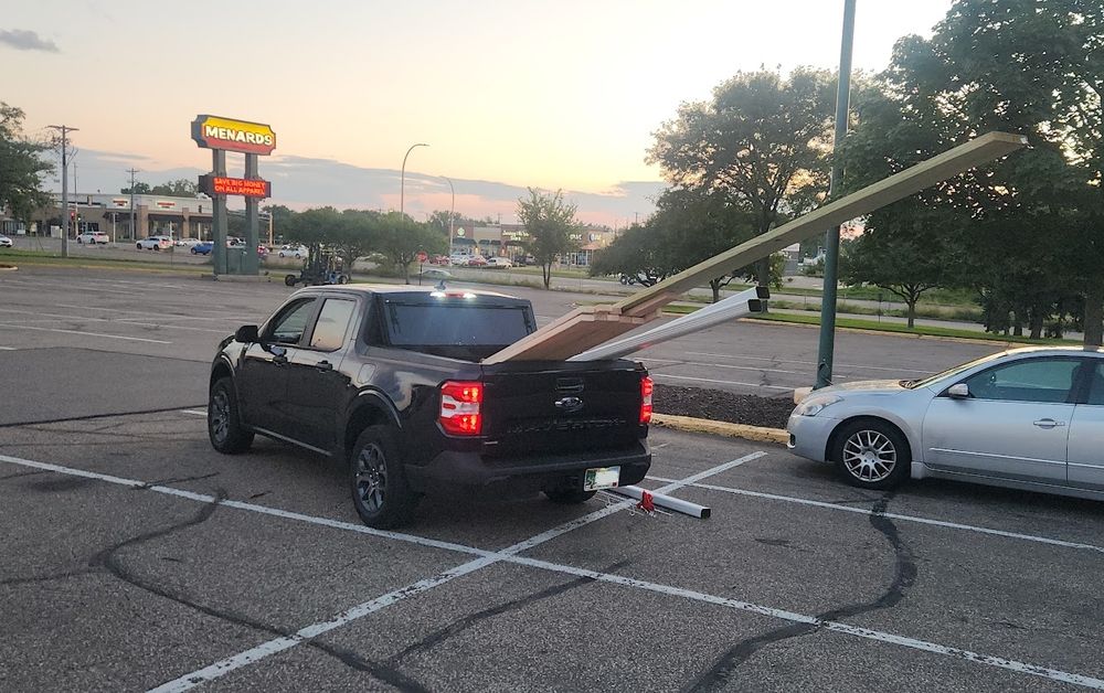 Truck with a short bed that has too many long things on the back.