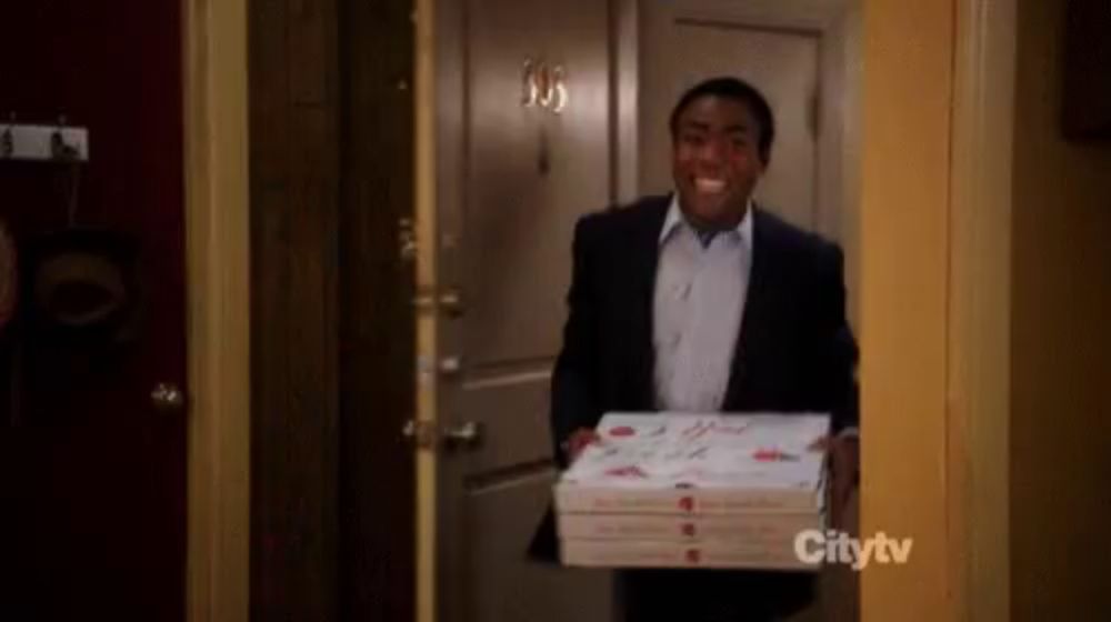 a man in a suit is carrying a stack of pizza boxes .