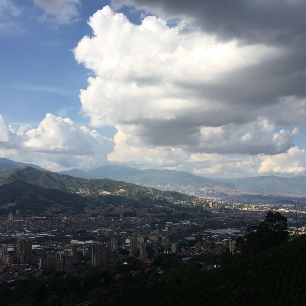 A city skyline with mountains and dramatic clouds 
