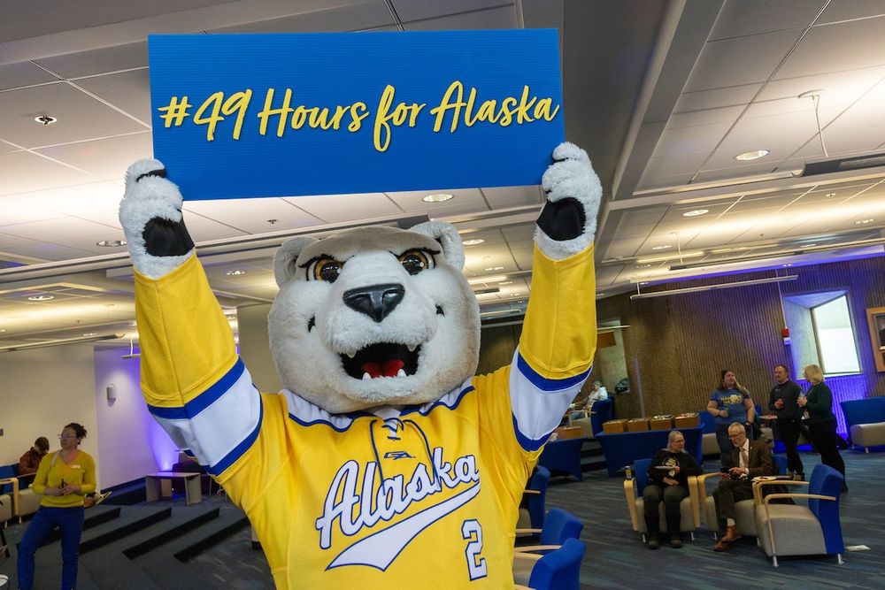 UAF mascot Nook holds up a sign that reads #49HoursforAlaska