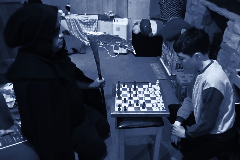 black and white photograph of me dressed as the grim reaper playing chess with my son