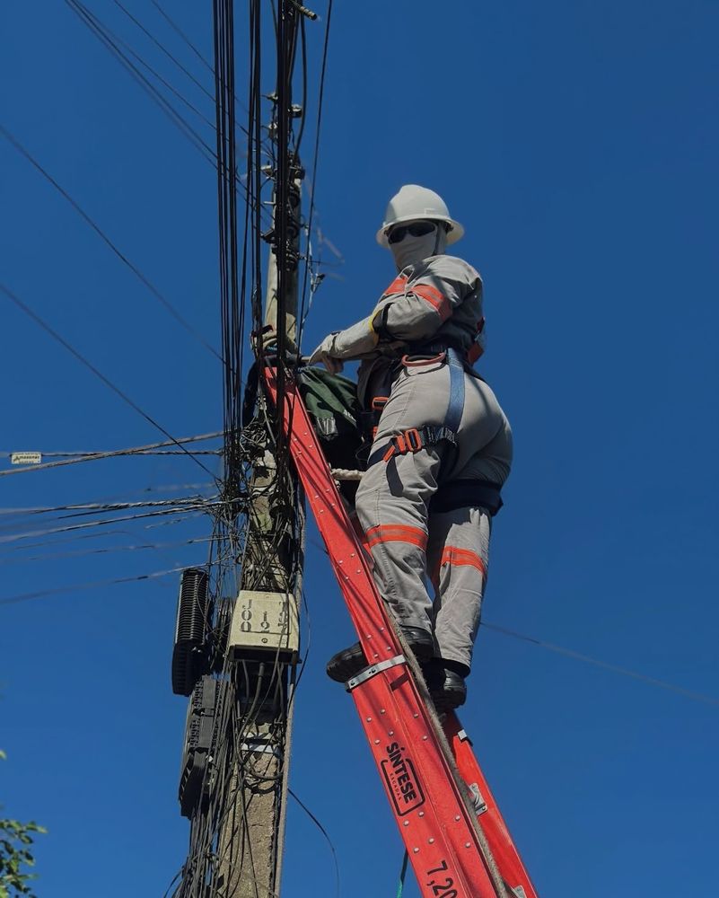 um eletricista muito rabudo em cima da escada trabalhando no poste