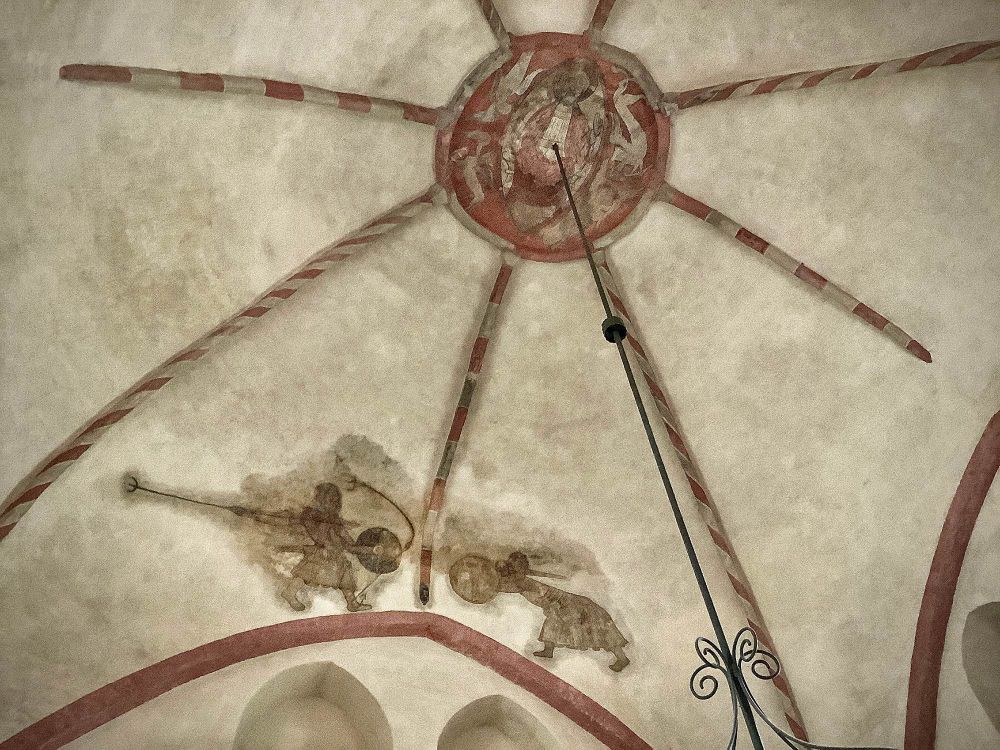 Another version of the same duel scene as above, painted on the vault of a church. The figures are blurry, but they are in the same positions, with the left one about to hurl a spear while holding a round shield, and the right one taking Second Guard behind a similar shield or large buckler. These figures appear to have long cloth tunics, hair, and boots. The one on the left has a sword scabbard or dagger stuck through his belt pouch, fourteenth-century style. A spear, presumably just hurled by the man on the right, has struck the ground near the other figure’s foot, and it’s bending in crazy curves. Photo by Jur Kuipers.