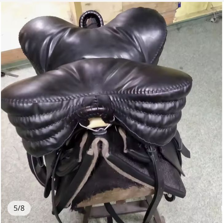 A modern Circassian saddle, seen from behind. The tree holds the seat high over the horse’s back. There is a very heavily-stuffed four-lobed leather seat cushion attached at either end to the saddlebows.