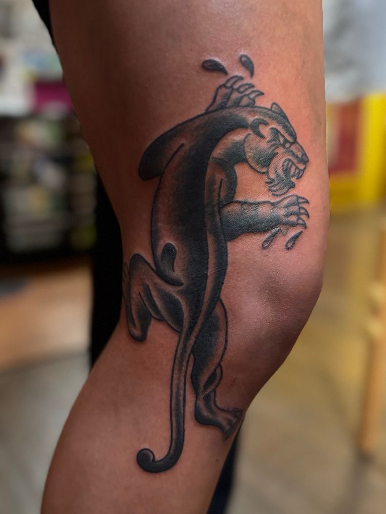Black and grey panther tattoo on the side of knee.