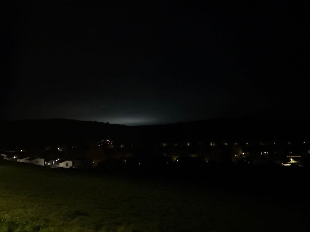Lichtdämmerung im Dunkeln hinter einem Hügelsattel