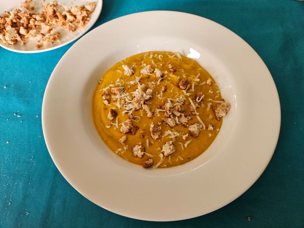 Bord pompoensoep met verkruimelde bitterkoekjes en parmezaan