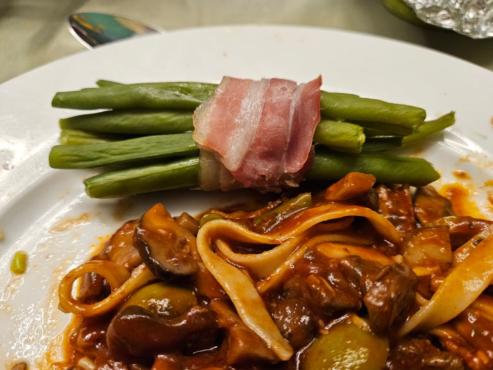 Sperziebonen in spek gewikkeld met tagliatelle met saus van lamsvlees, champignons en olijven
