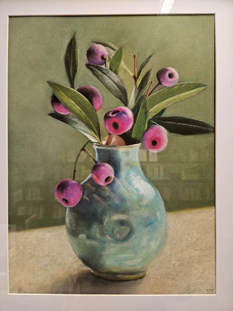 Schilderij van blauwachtige vaas met takken met langwerpige bladeren en roze bolletjes voor een groene achtergrond. In het glas wordt een wand vol boeken weerspiegeld