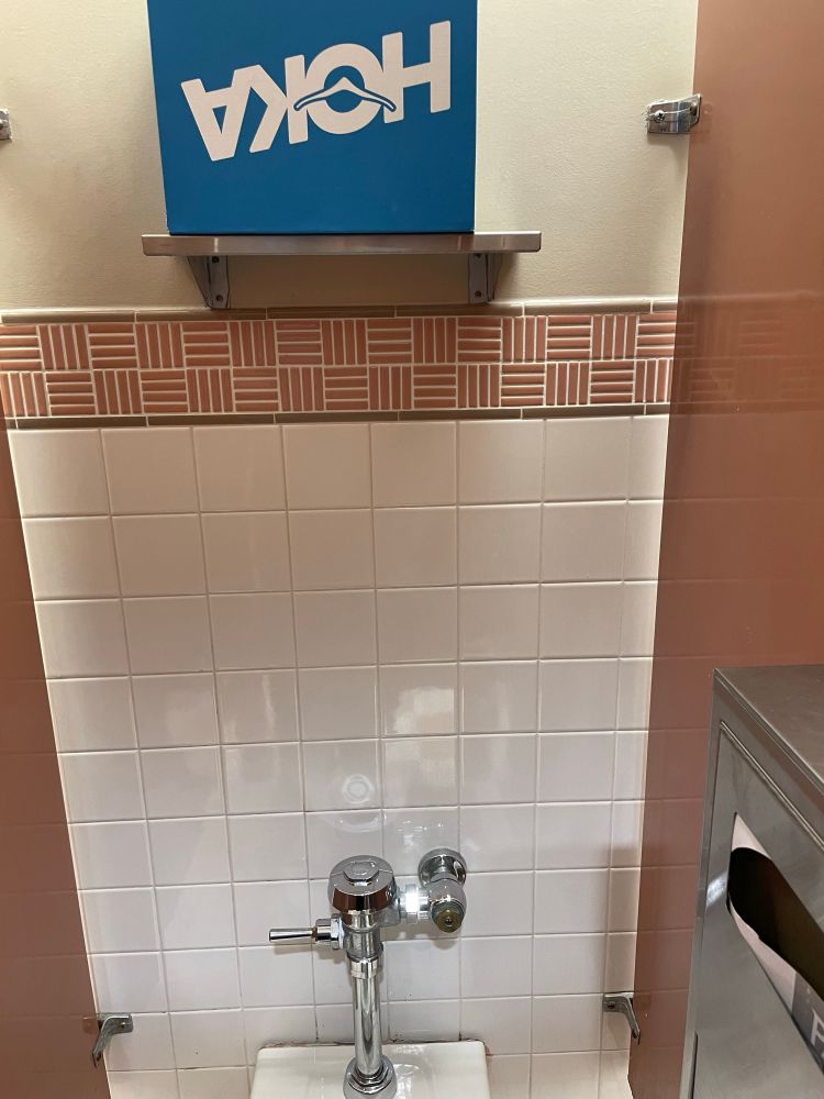 A blue box with the word Hoka on the side sits on a top shelf above the toilet. 