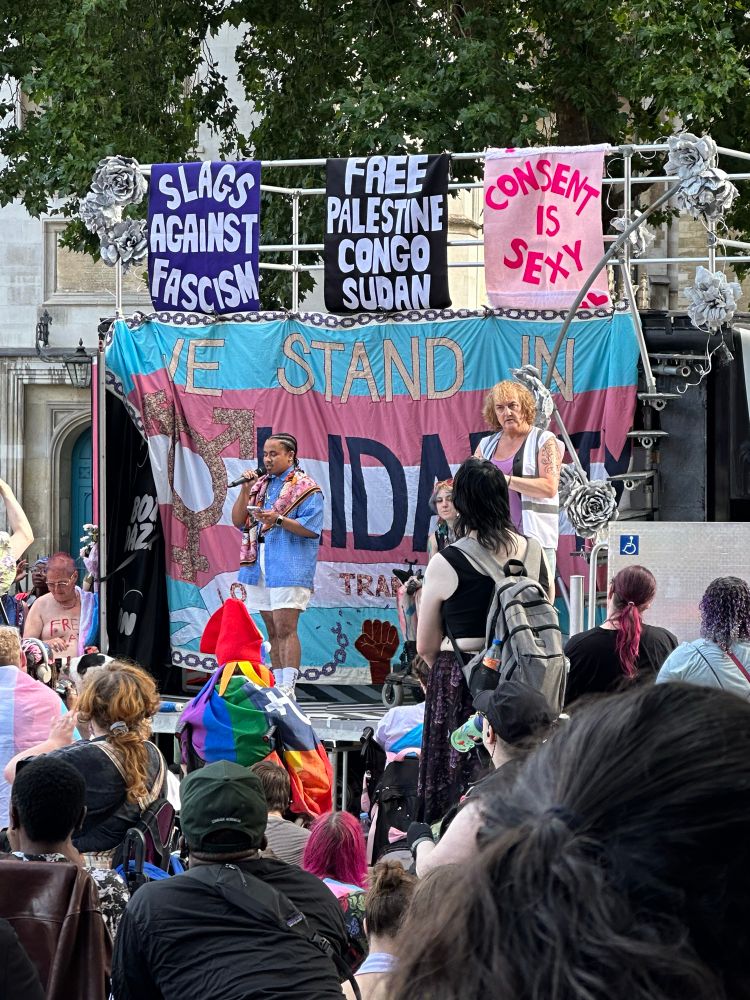 Ki Griffin on stage with white shorts and a blue shirt and pink scarf 
