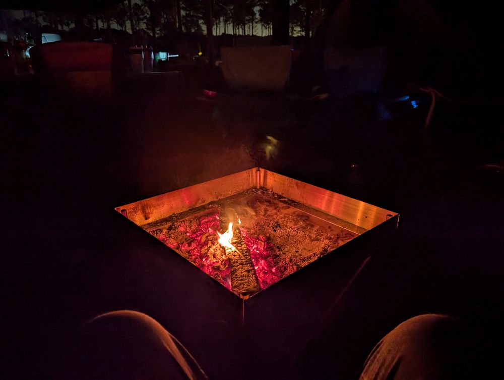 Me sitting in front of a fire pit with a small fire in it