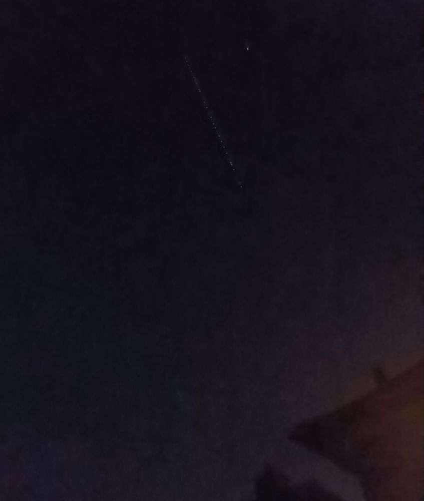 Grainy picture of a chain of Starlink satellites in the night sky