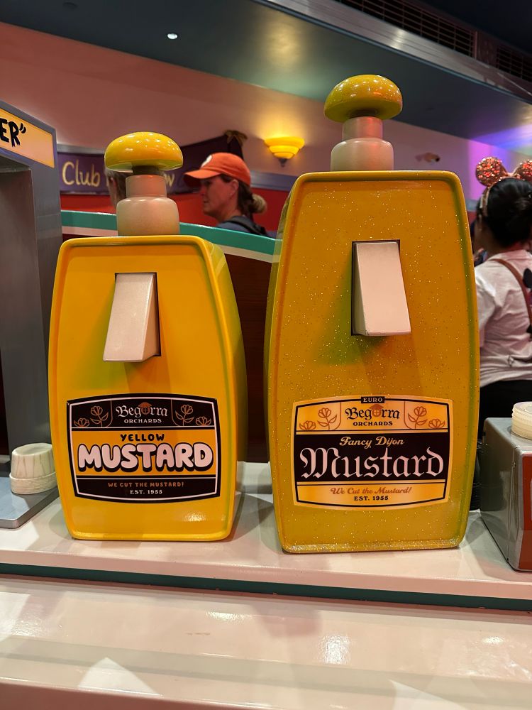 Prop mustard dispensers in toontown. The first one is plain yellow mustard, the second is glittery “fancy Dijon”
