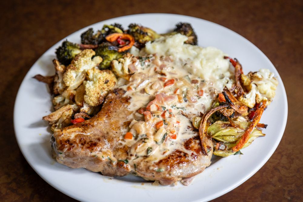 Pork chop dinner with mashed potatoes and roasted vegetables.