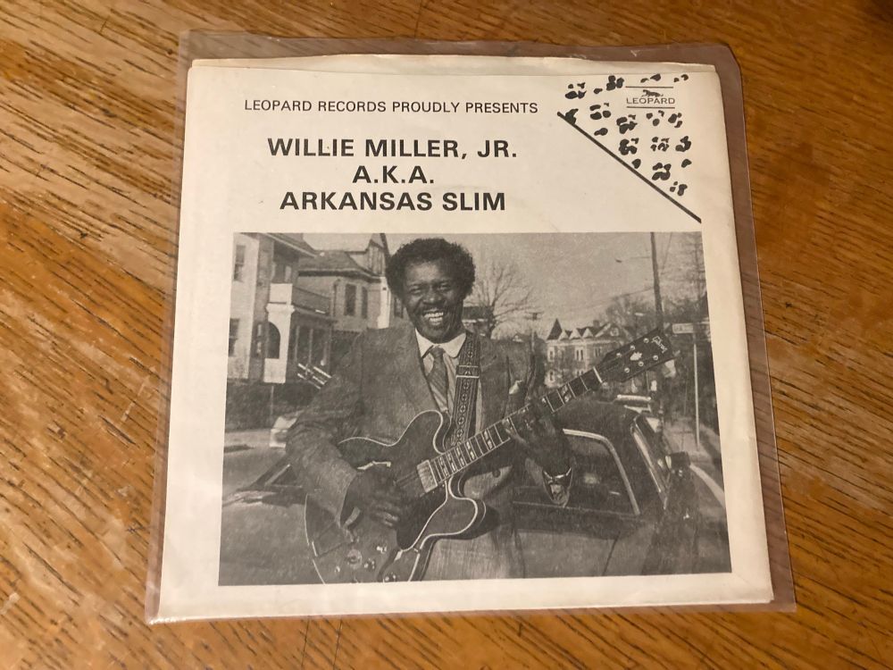 45 rpm record sleeve
(B&W  photo of black man on a street with electric Gibson guitar.
Houses & cars are visible behind him.
Text:

LEOPARD RECORDS PROUDLY PRESENTS
WILLIE MILLER, JR.
A.K.A.
ARKANSAS SLIM